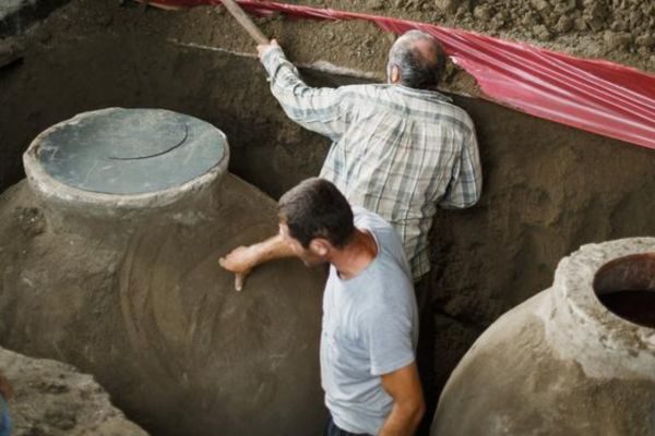 Zwei Männer arbeiten an Tonfässer am Chateau Mukhrani
